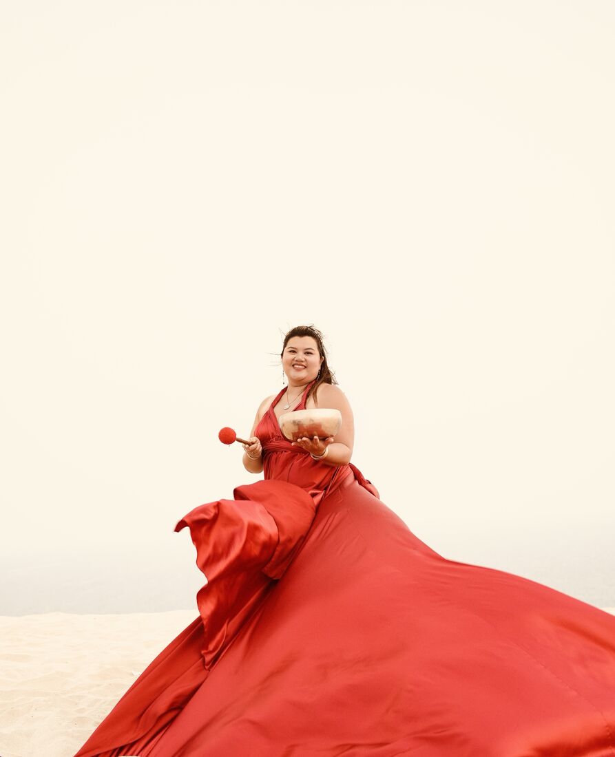 Vivi in a flowing red dress holding a singing bowl